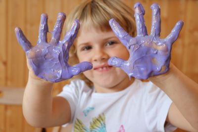 Kind mit lila Fingerfarbe an den Händen