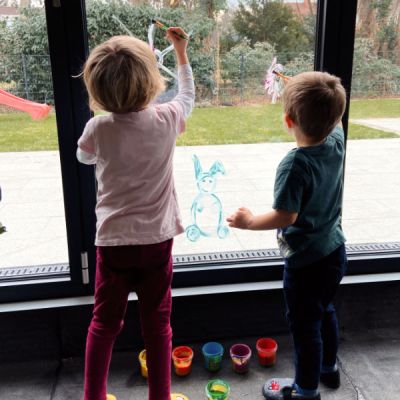 Kinder bemalen Fensterscheibe mit Fingerfarben