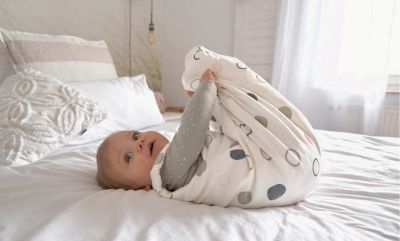 Baby trägt Bio Ganzjahresschlafsack im Bett