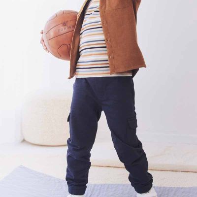 Kind mit Basketball trägt Kinderkleidung Hose und Shirt