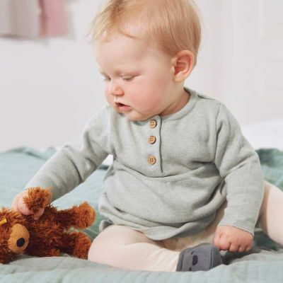 Baby mit Teddy trägt Bio Babykleidung