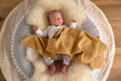 Baby auf Lammfell mit Decke bedeckt