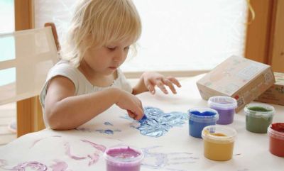 Kind malt mit Töpfchen mit Fingermalfarbe