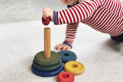 Kind spielt auf Teppich mit Holz Steckspielzeug