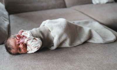 Baby auf Couch im grauen Strampelsack