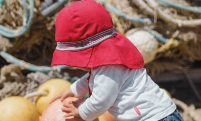 Baby trägt roten Sonnenhut aus Bio Baumwolle