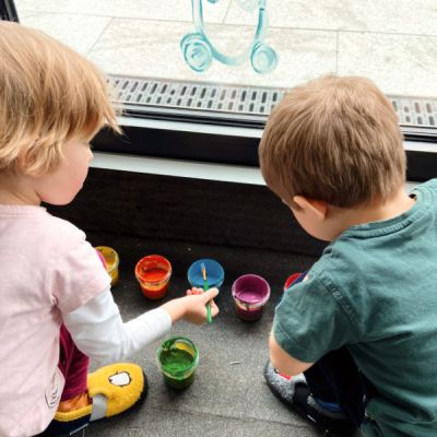 Kinder bemalen Fenster mit Fingermalfarben